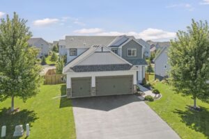 A two-story modern suburban house on Fairchild Way with gray siding, a three-car garage, and a well-maintained lawn, surrounded by trees and neighboring homes under a blue sky—perfect for real estate photos.