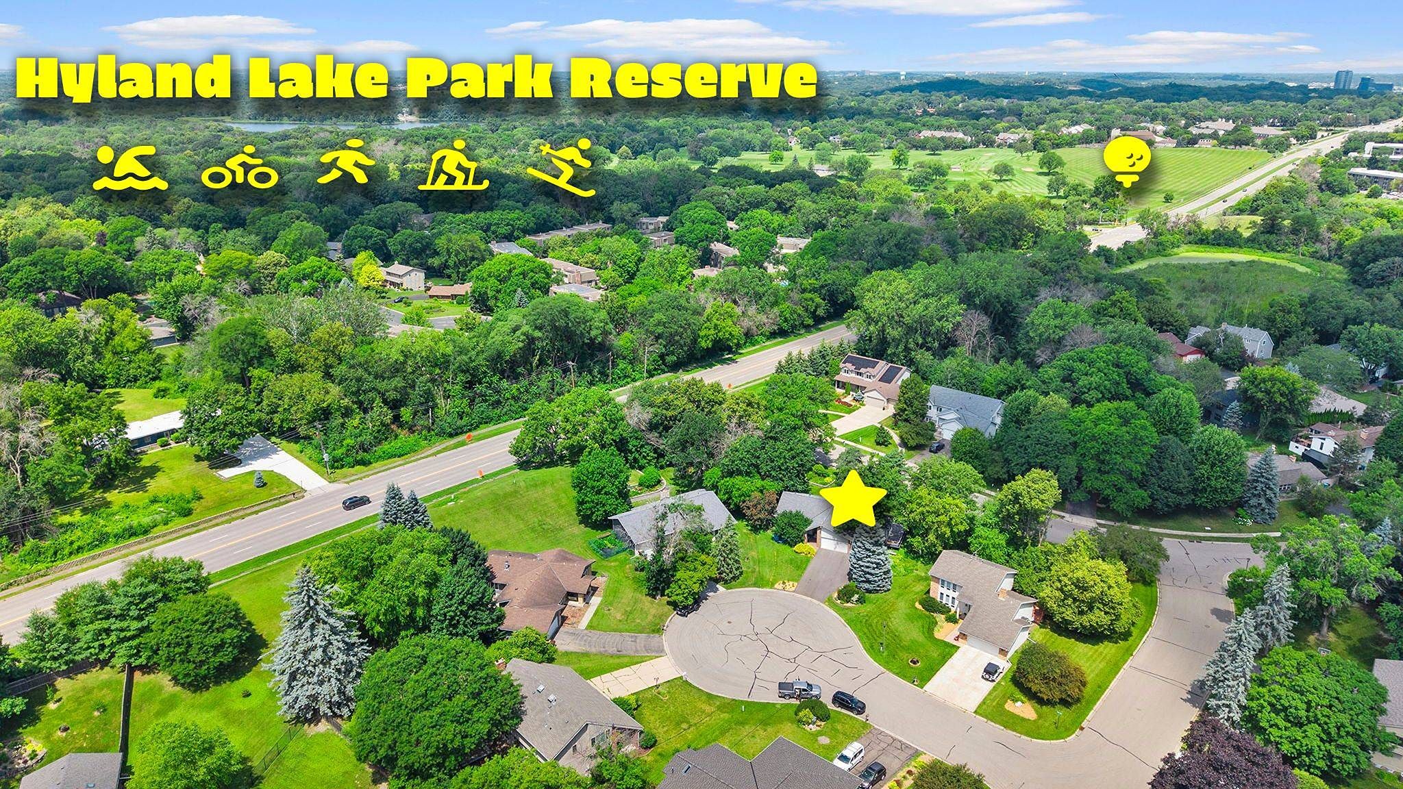 Aerial view of a suburban neighborhood near Hyland Lake Park Reserve, with icons for swimming, biking, hiking, running, and skiing. A yellow star and pin highlight specific houses and locations. Lush trees and green spaces surround the area.
